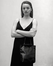 Load image into Gallery viewer, Pazar I Pazar Tote Nano Black I black I front view I showing iconic SAGAN closing system and strap detail I wearing by a model I black and white picture